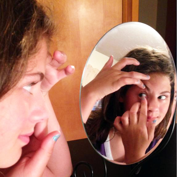 image of woman inserting contact lense